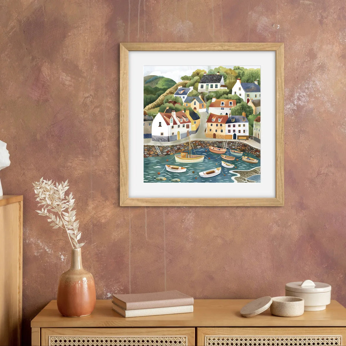 Artwork of a colourful coastal village with cottages and boats in a harbour.